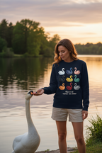 Woman feeding a swan by a lake at sunset with a colorful swan design on her shirt.