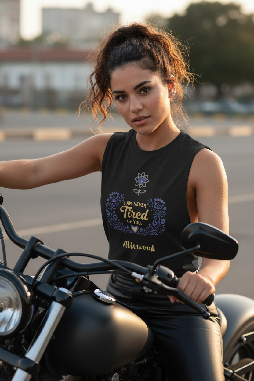 Woman sitting on a motorcycle wearing a black sleeveless shirt with text and graphics.