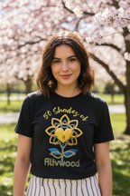Person wearing a black t-shirt with a colorful design and text, standing outdoors with cherry blossom trees in the background.