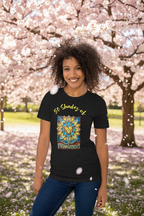 Person wearing a black t-shirt with a colorful design and text, standing in a park with cherry blossoms.