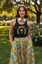 Woman wearing a black tank top with a floral design and a yellow skirt in a park setting.