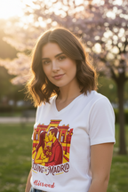 Woman wearing a white t-shirt with a colorful graphic design in a park with cherry blossoms.